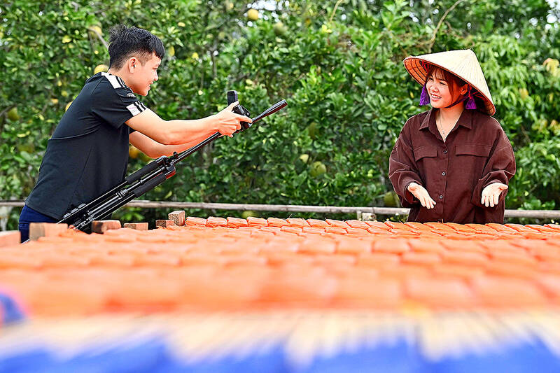  TikToker Vi Thi Anh, right, is filmed by her husband to shoot a TikTok video drying noodles at her workshop in Bac Giang province. Photo AFP  
