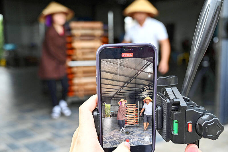  A mobile phone being used to shoot a video of TikToker Vi Thi Anh taking noodles to dry last month for TikTok at her workshop in Bac Giang province. Photo AFP  